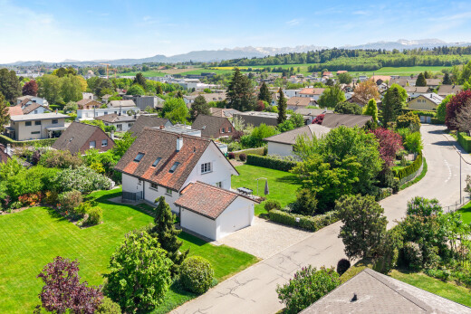 outdoor house with decorative driveway, a residential view, a lawn, a garage, and a mountain view