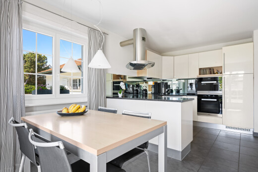 kitchen featuring dark countertops, range hood, a peninsula, white cabinetry, and a kitchen bar