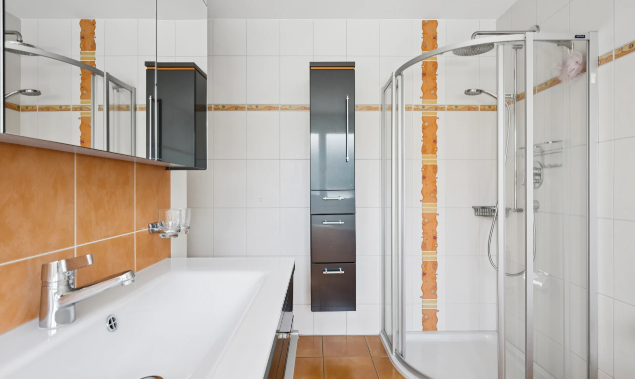 salle de bains avec évier, miroir, douche, salle de bain complète, et tile wall
