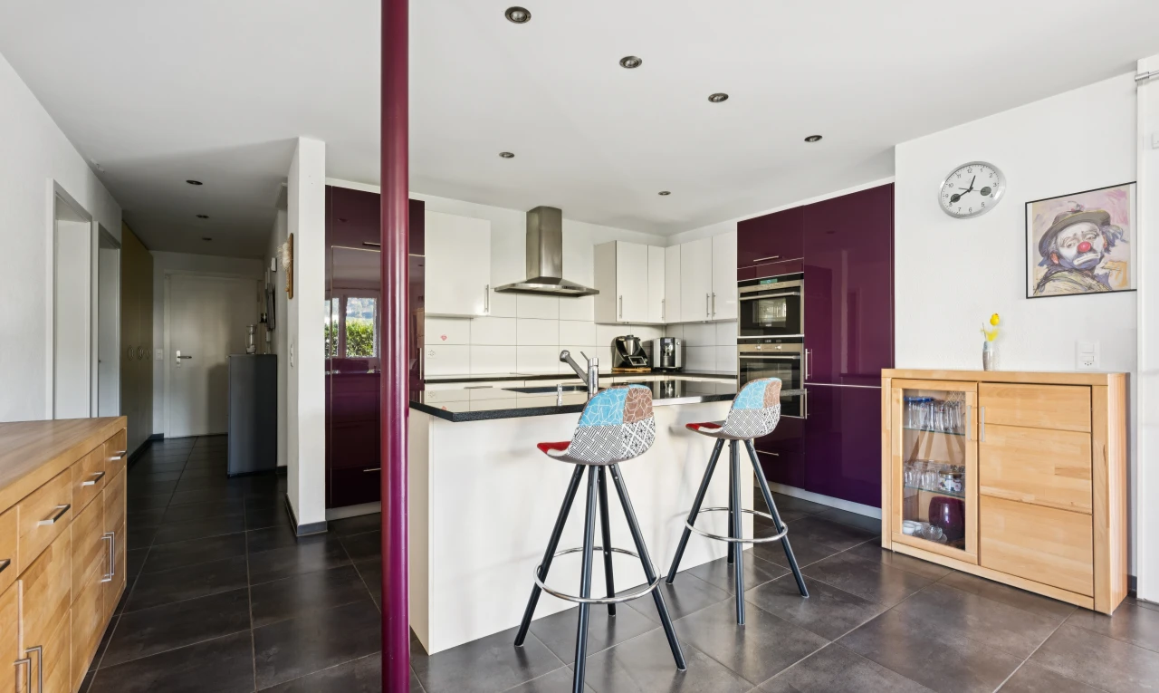 cuisine avec kitchen bar, bar de cuisine, hotte, dark floor, et drywall