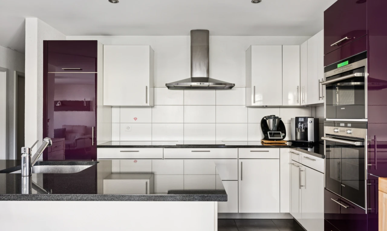cuisine avec hotte, dark countertops, armoires blanches, white cabinets, et dark floor