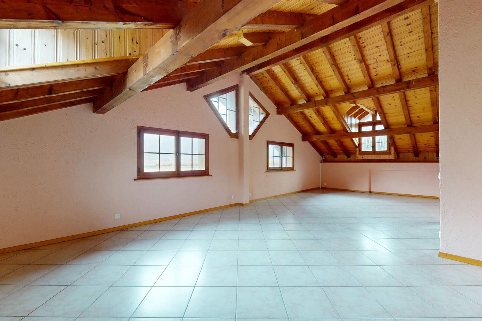 pièce vide avec plafond en bois, plafond voûté, plinthes murales, lumière naturelle, et plafond à poutres