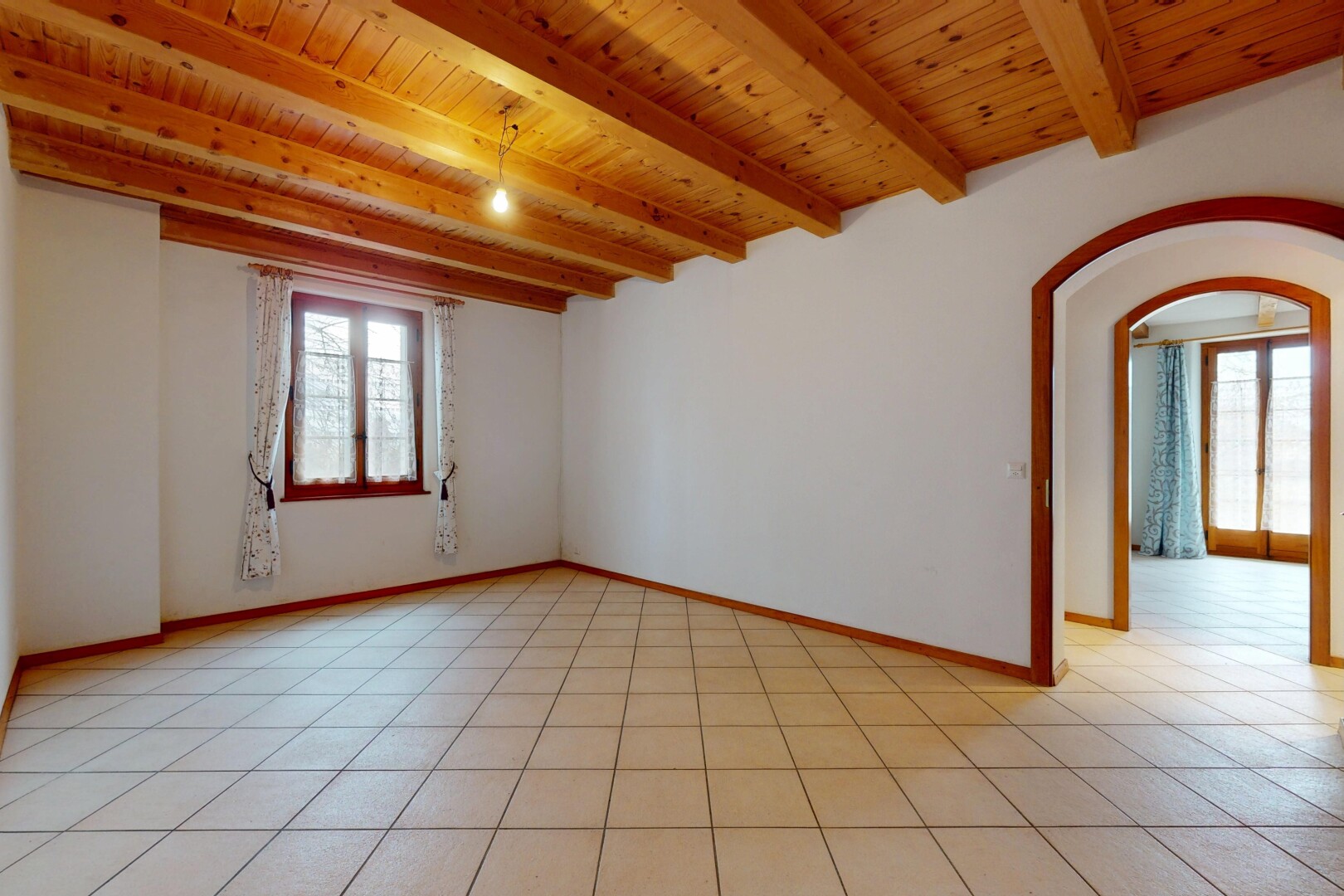 pièce vide avec plafond à poutres, passages en arc, lumière naturelle, plafond en bois, et cloison sèche