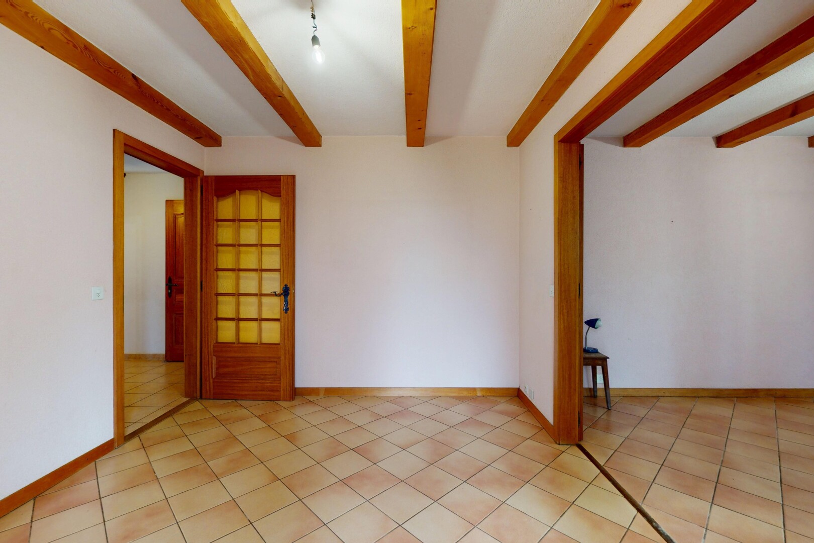 pièce vide avec cloison sèche, plafond à poutres, sol en carrelage, et plinthes murales