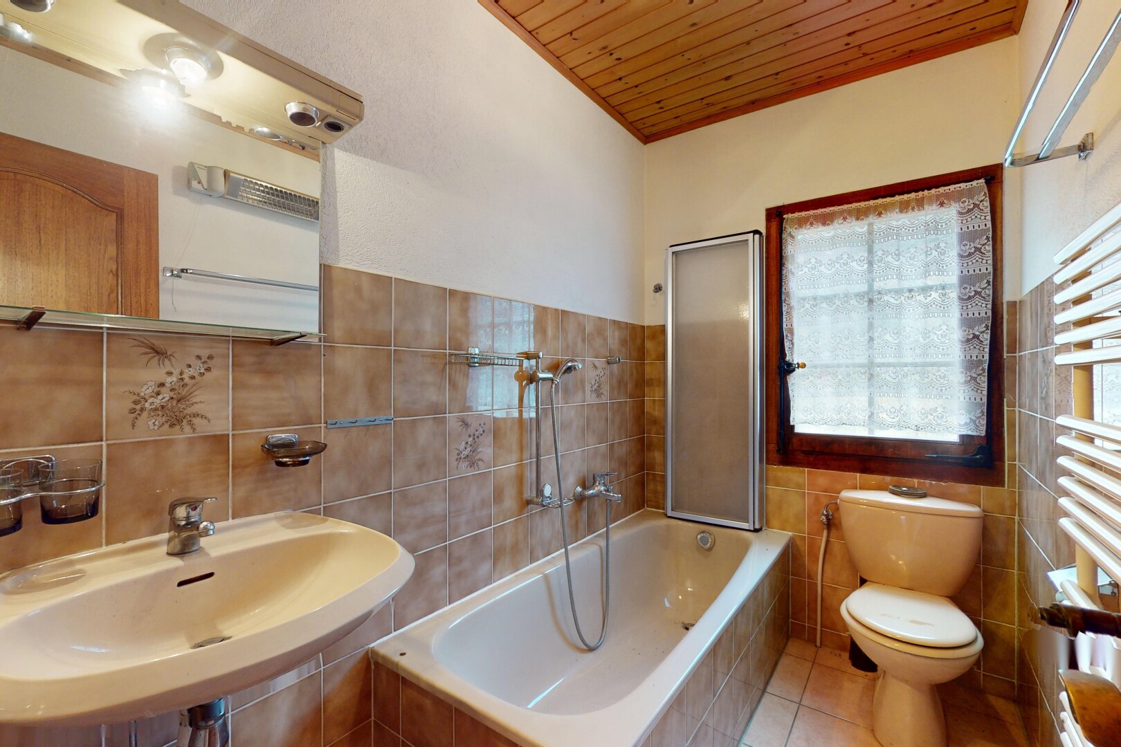 salle de bains avec sol en carrelage, plafond en bois, évier, mur en carrelage, et lumière naturelle