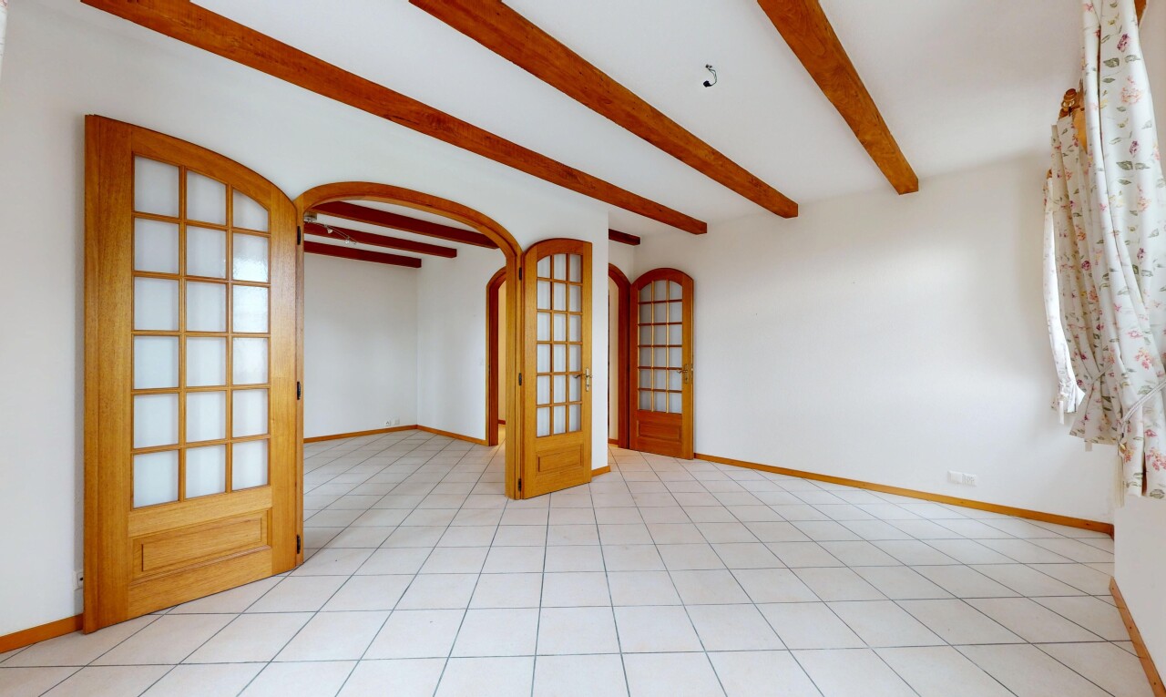 pièce vide avec plafond à poutres, passages en arc, et plinthes murales