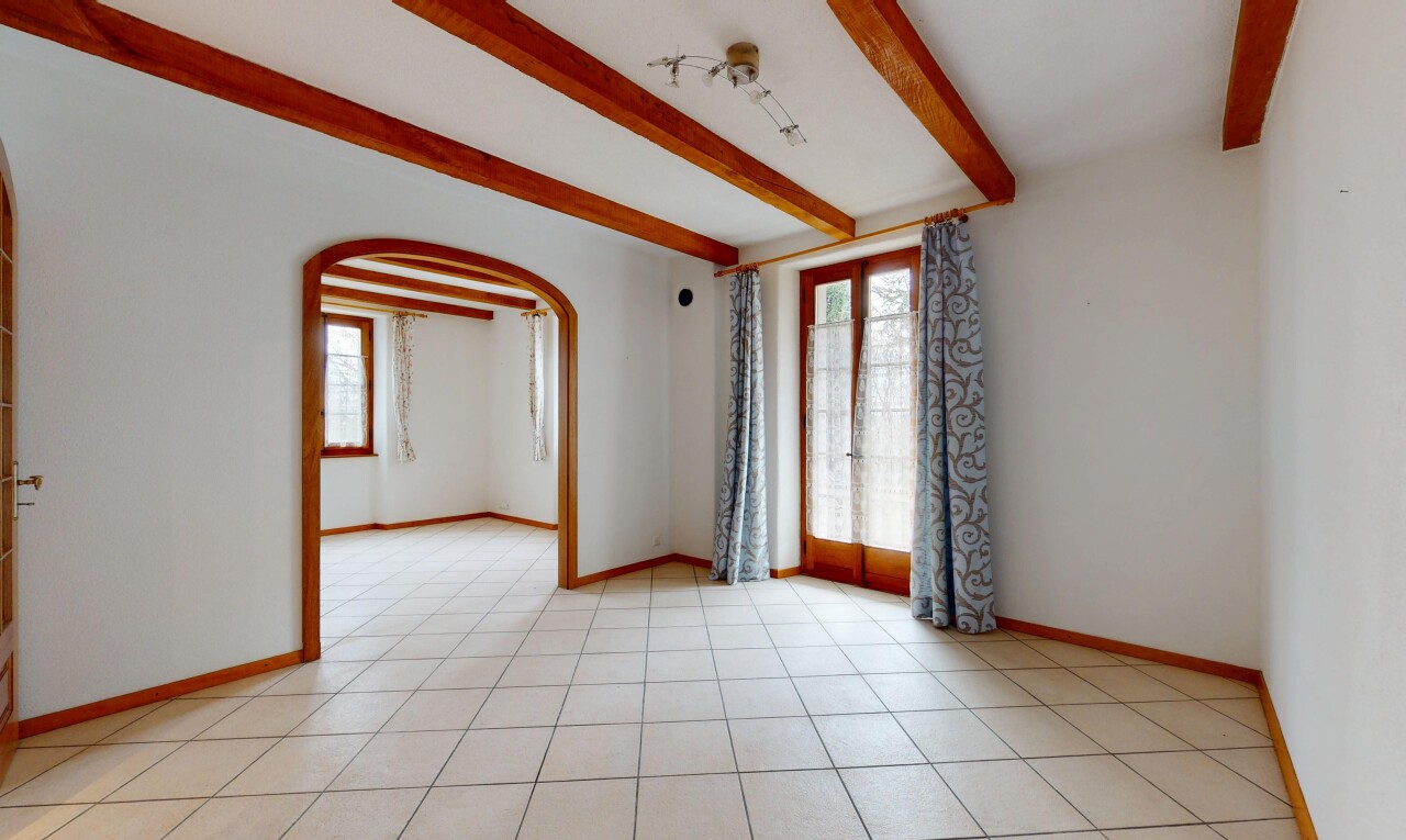 pièce vide avec cloison sèche, plafond à poutres, lumière naturelle, et passages en arc