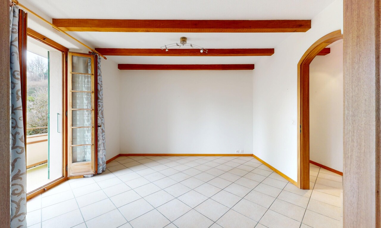 pièce vide avec lumière naturelle, cloison sèche, plafond à poutres, et passages en arc