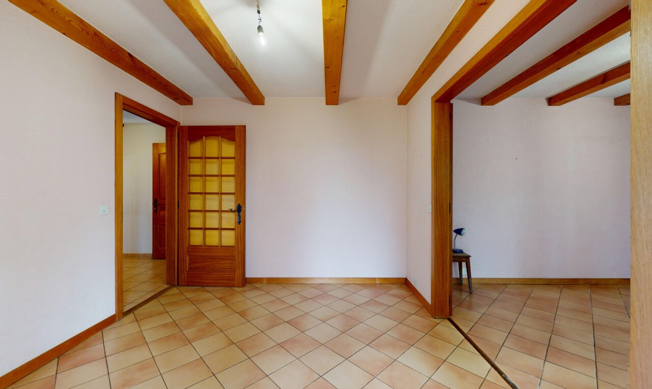 pièce vide avec cloison sèche, plafond à poutres, sol en carrelage, et plinthes murales