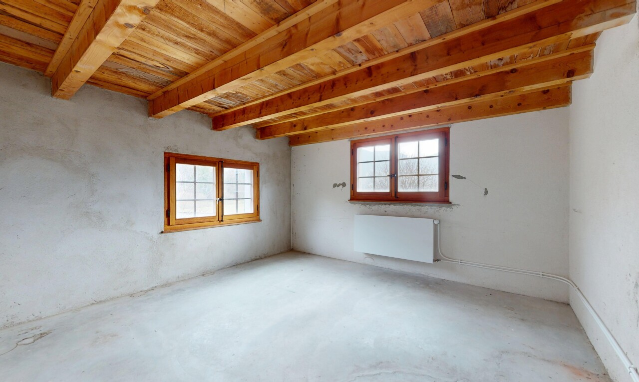 pièce vide avec sol en béton, plafond à poutres, radiateur, lumière naturelle, et plafond en bois