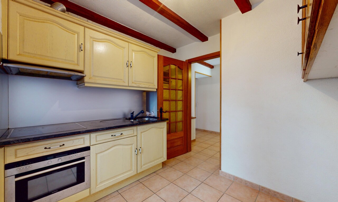 cuisine avec plaque de cuisson, armoires crème, évier, four, et plans de travail