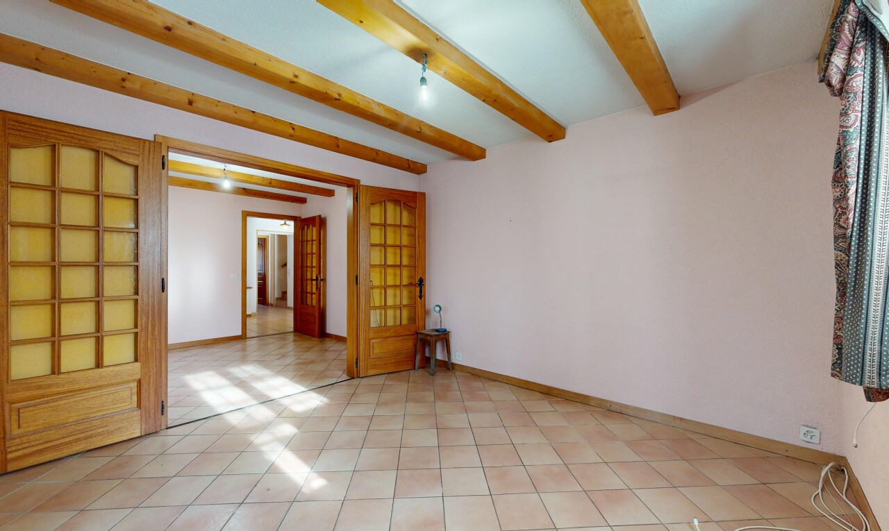 pièce vide avec portes-fenêtres, cloison sèche, plafond à poutres, et plinthes murales
