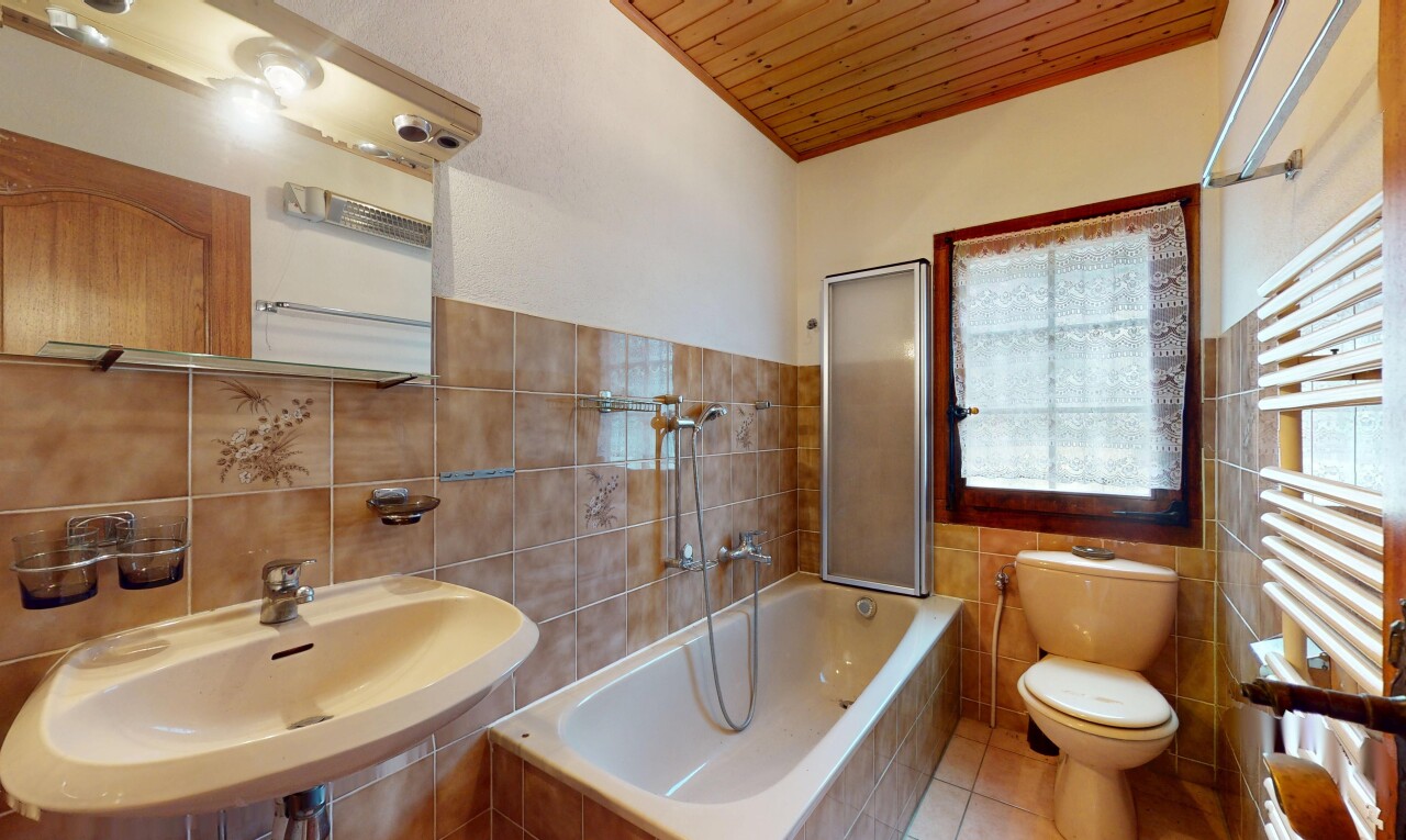 salle de bains avec sol en carrelage, plafond en bois, évier, mur en carrelage, et lumière naturelle