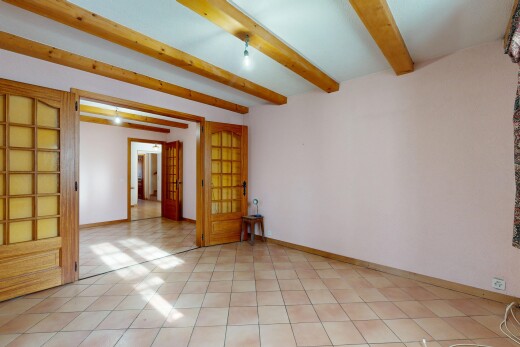 pièce vide avec portes-fenêtres, cloison sèche, plafond à poutres, et plinthes murales