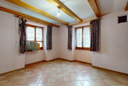 pièce vide avec lumière naturelle, plafond à poutres, et plinthes murales