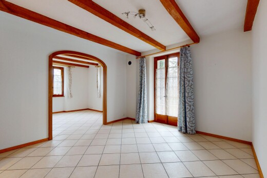 pièce vide avec cloison sèche, plafond à poutres, lumière naturelle, et passages en arc