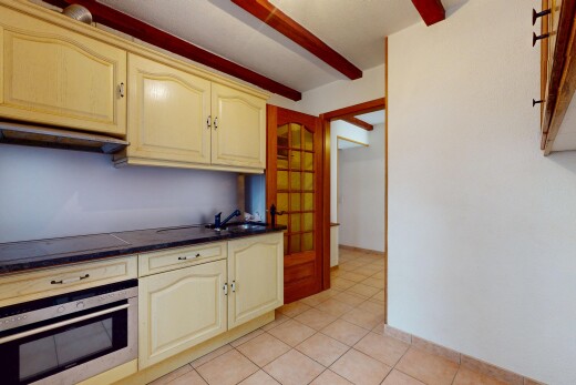 cuisine avec plaque de cuisson, armoires crème, évier, four, et plans de travail