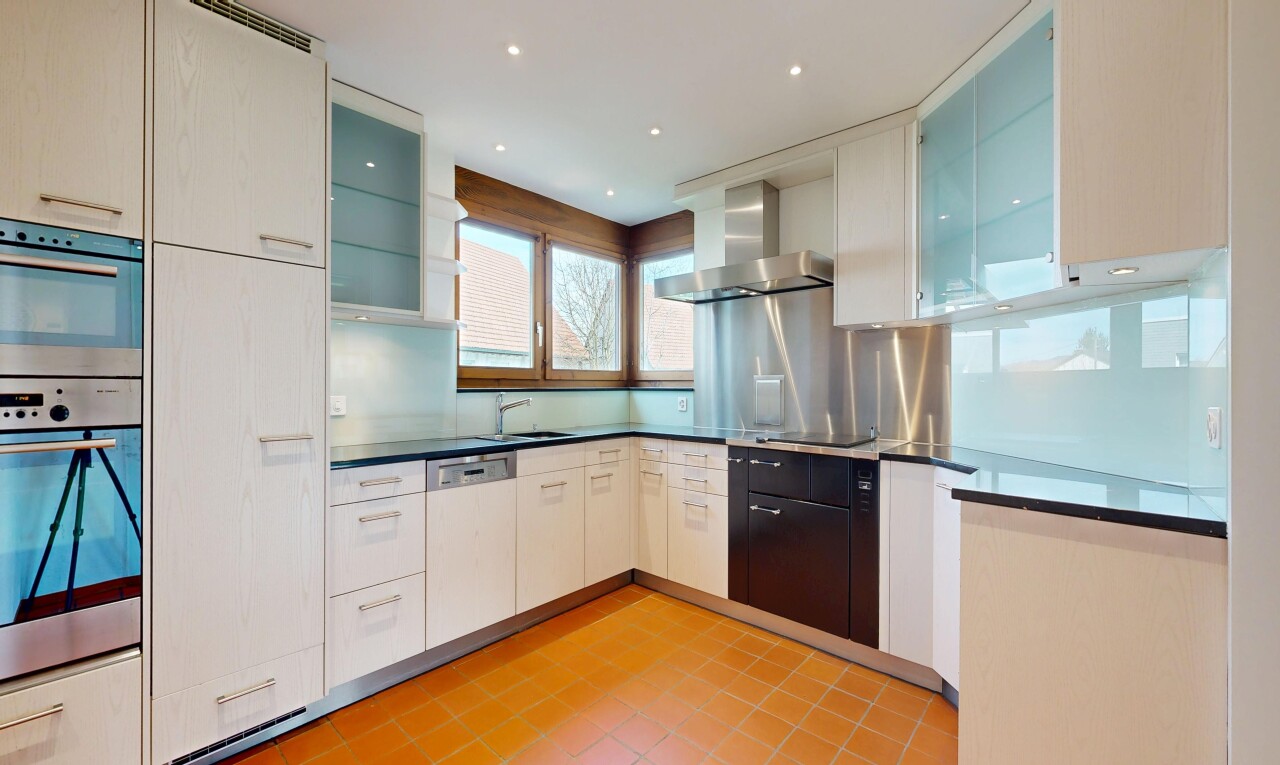 cuisine avec light floor, hotte, glass insert cabinets, armoires avec insert en verre, et dark countertops