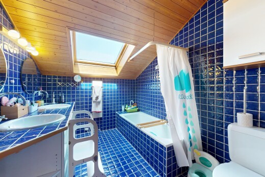 salle de bains avec évier, mur en carrelage, plafond voûté, toilette, et plafond en bois