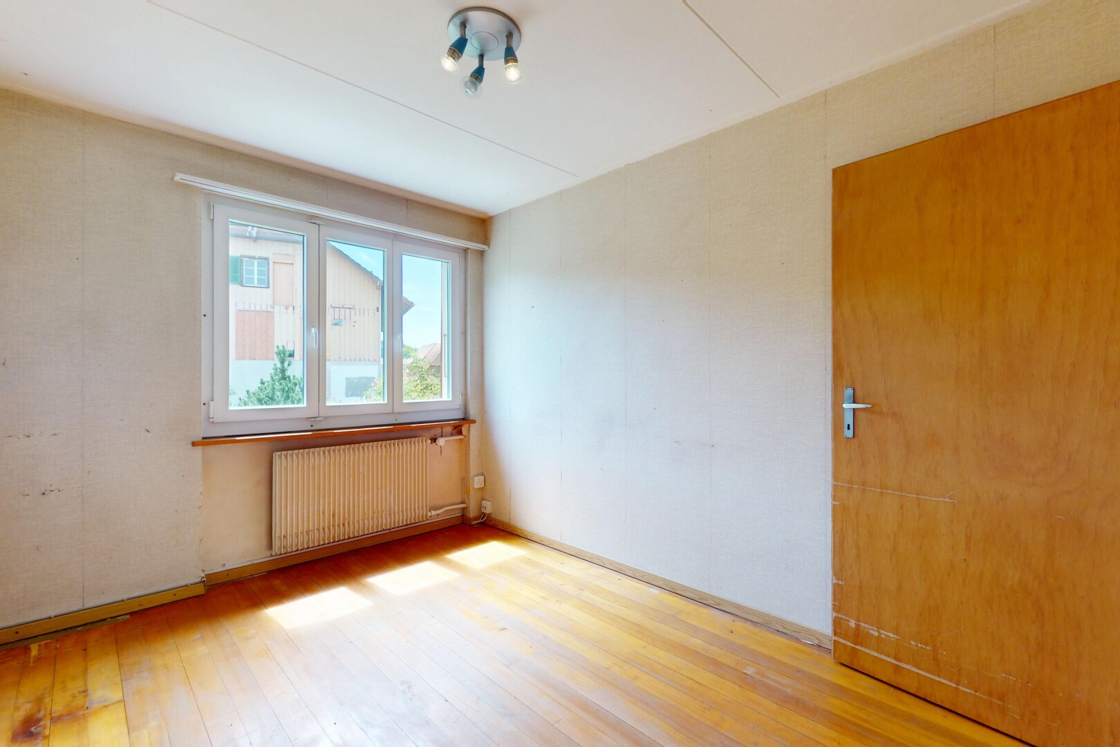 pièce vide avec natural light, lumière naturelle, radiateur, wood finish floor, et sol en finition bois