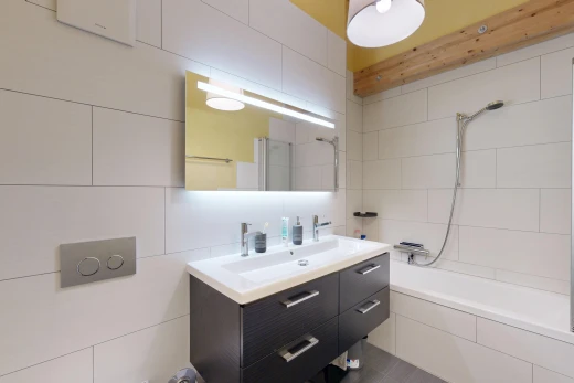 salle de bains avec salle de bain complète, lavabo (ou coiffeuse selon le contexte), miroir, douche-bain combinés, et mur en carrelage