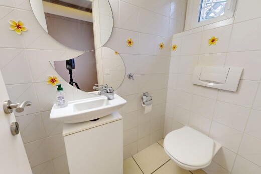 salle de bains avec toilette, miroir, lavabo (ou coiffeuse selon le contexte), inside property, et tile wall