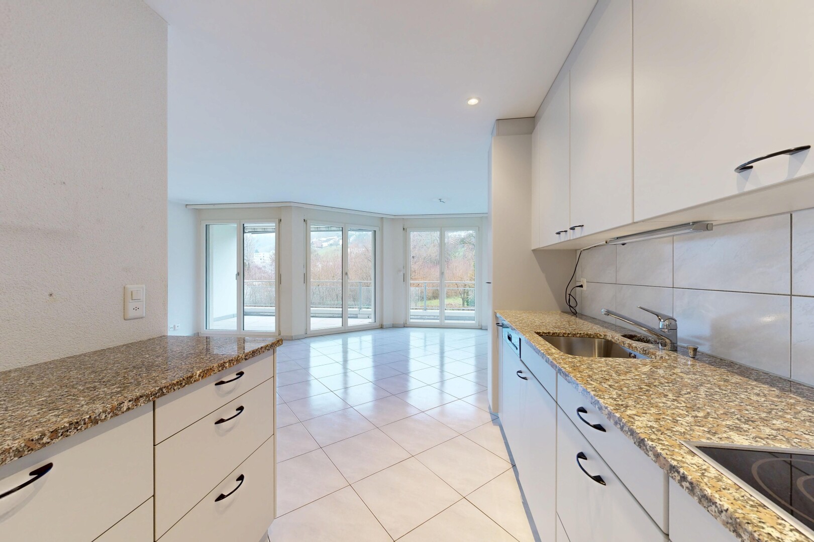 cuisine avec dosseret, backsplash, plans de travail en pierre, plaque de cuisson, et armoires blanches