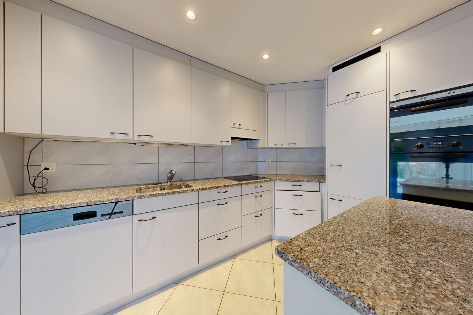 cuisine avec plans de travail en pierre, lave-vaisselle, inside property, dosseret, et backsplash