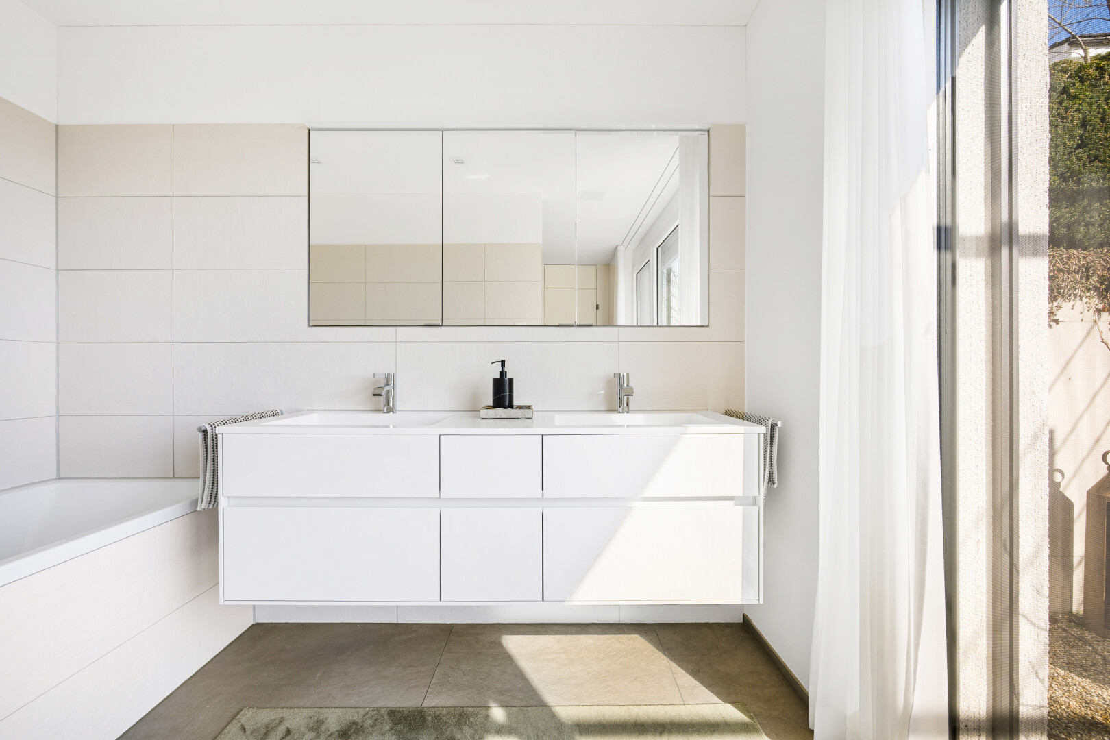 bathroom featuring double vanity, a bath, and tile walls