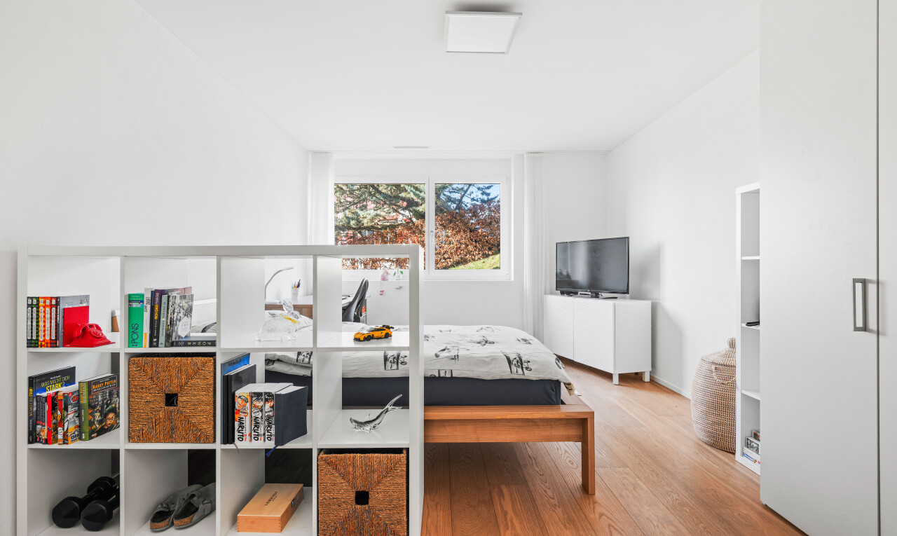 zimmer / schlafzimmer mit wood finish floor, holzfußboden, fernseher, inside property, und drywall