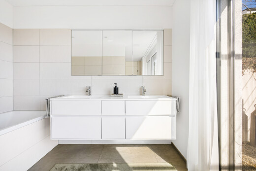 bathroom featuring double vanity, a bath, and tile walls