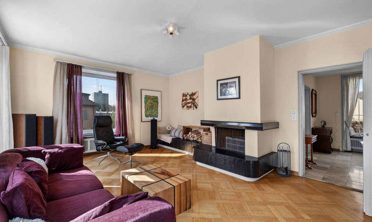 living room with crown molding, a fireplace with raised hearth, and parquet flooring
