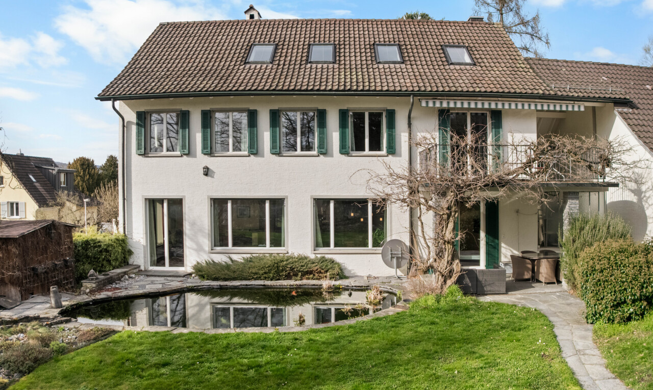 view of home featuring a lawn, a balcony, and a tile roof