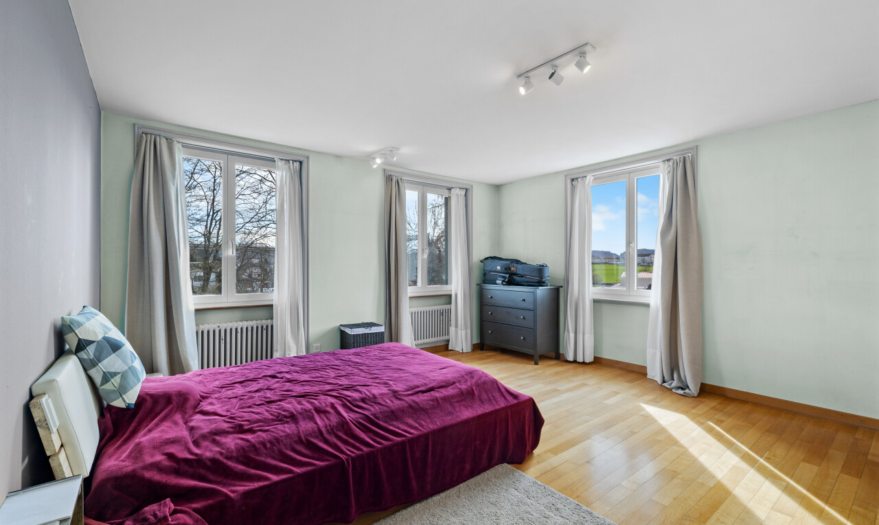 room with light wood-style flooring, radiator heating unit, rail lighting, and multiple windows