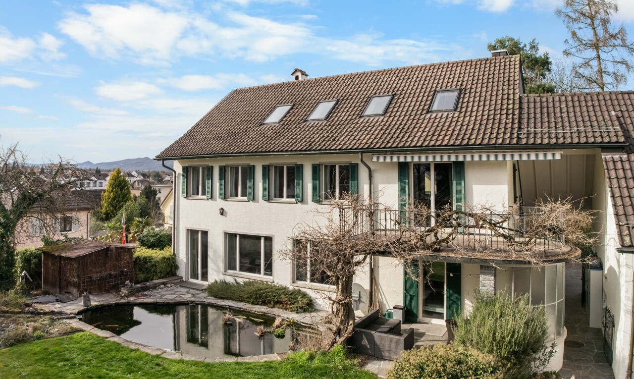 view of home with a balcony, a tile roof, a chimney, a patio, and stucco siding