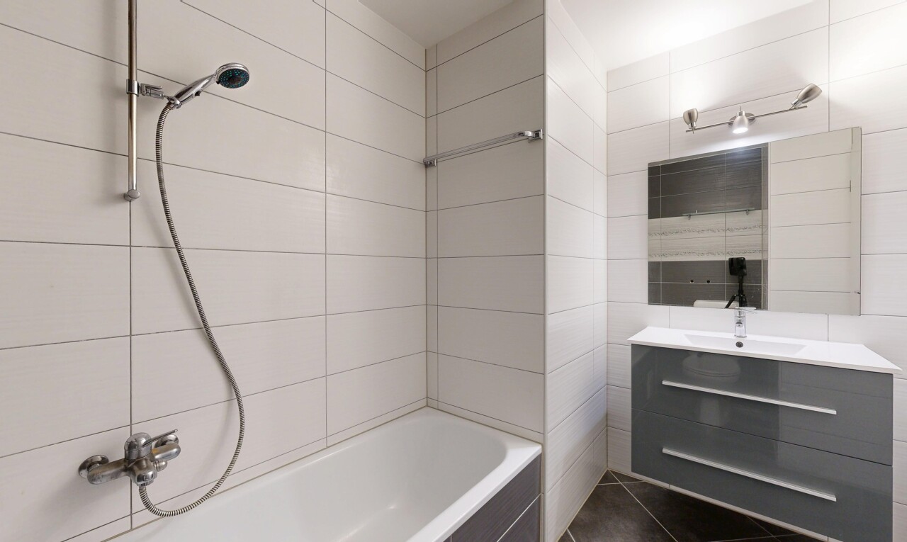 salle de bains avec lavabo (ou coiffeuse selon le contexte), miroir, mur en carrelage, tile wall, et salle de bain complète
