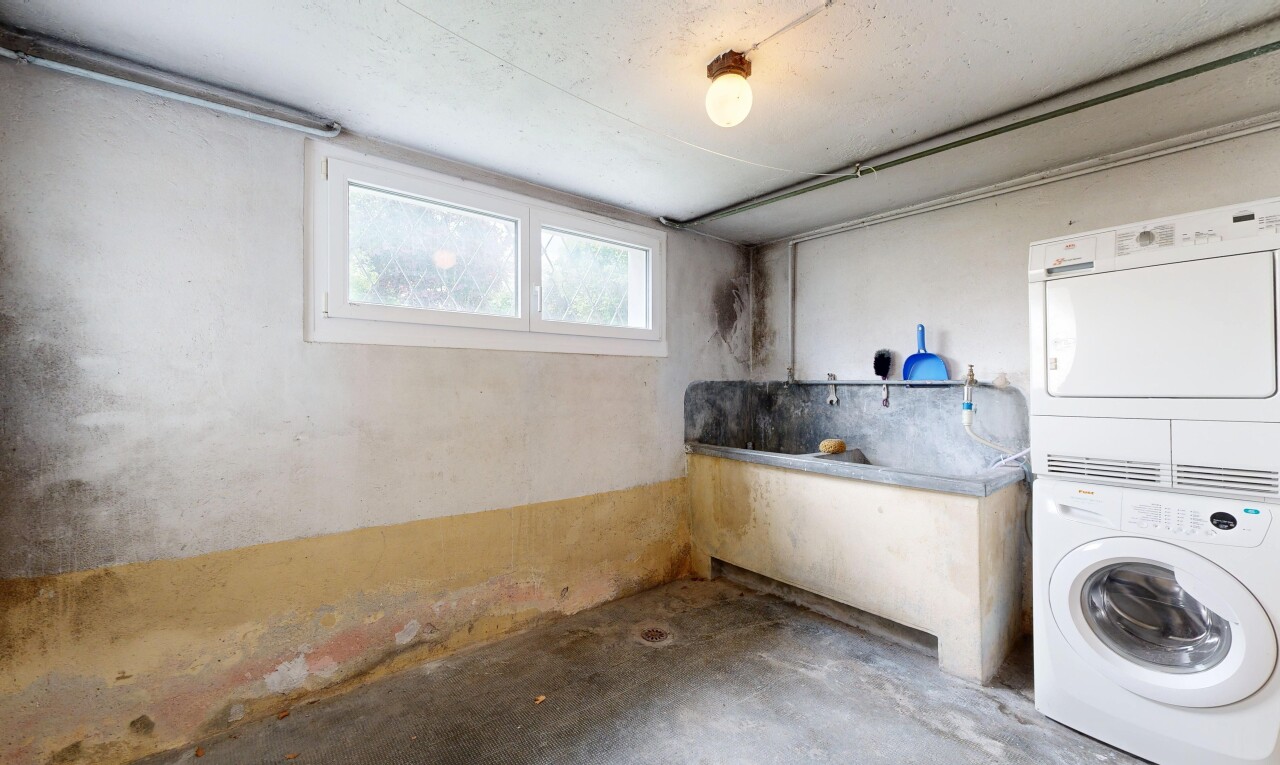 buanderie avec lave-linge et sèche-linge superposés, unfinished concrete floor, inside property, buanderie, et sol en béton