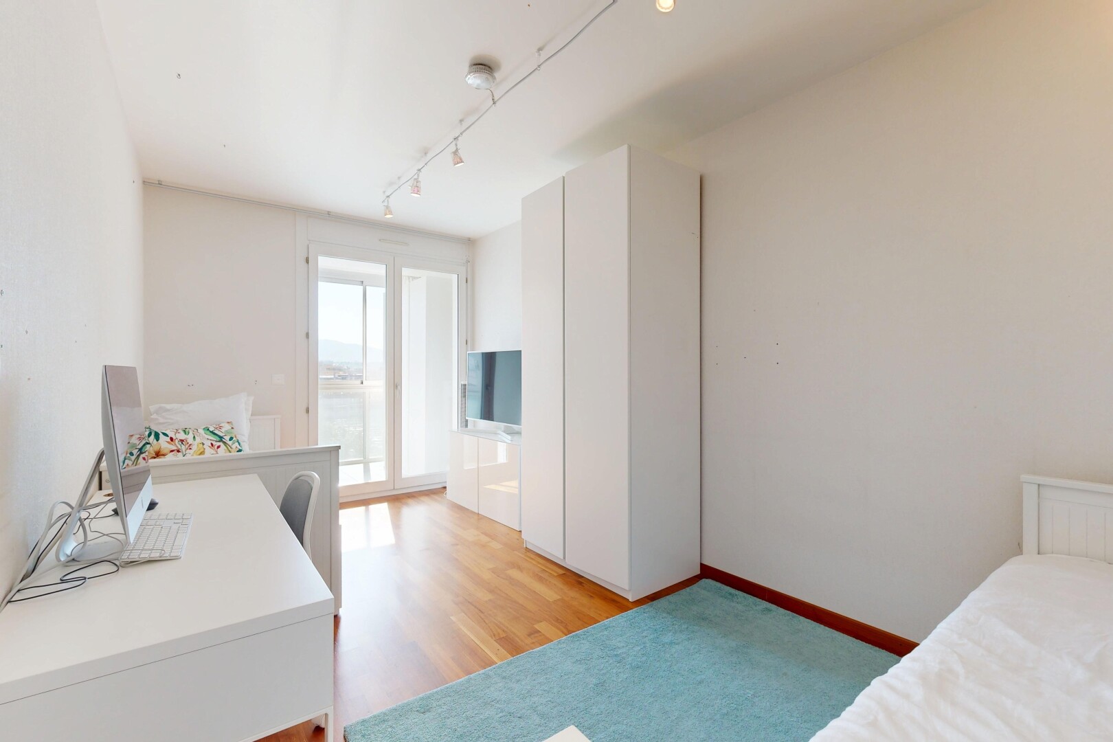 zimmer / schlafzimmer mit gipskartonwand, natürliches licht, holzfußboden, und fernseher