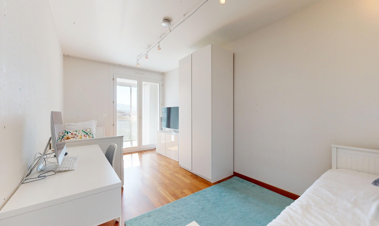 zimmer / schlafzimmer mit gipskartonwand, natürliches licht, holzfußboden, und fernseher