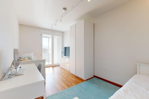 chambre avec cloison sèche, sol en finition bois, lumière naturelle, et télévision
