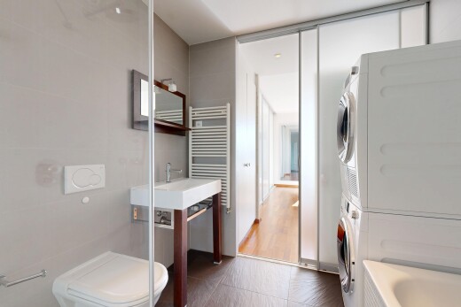 salle de bains avec toilette, salle de bain complète, lave-linge et sèche-linge superposés, bain, et chauffe-serviettes
