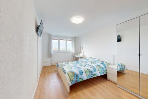 chambre avec placard, wood finish floor, sol en finition bois, télévision, et light floor