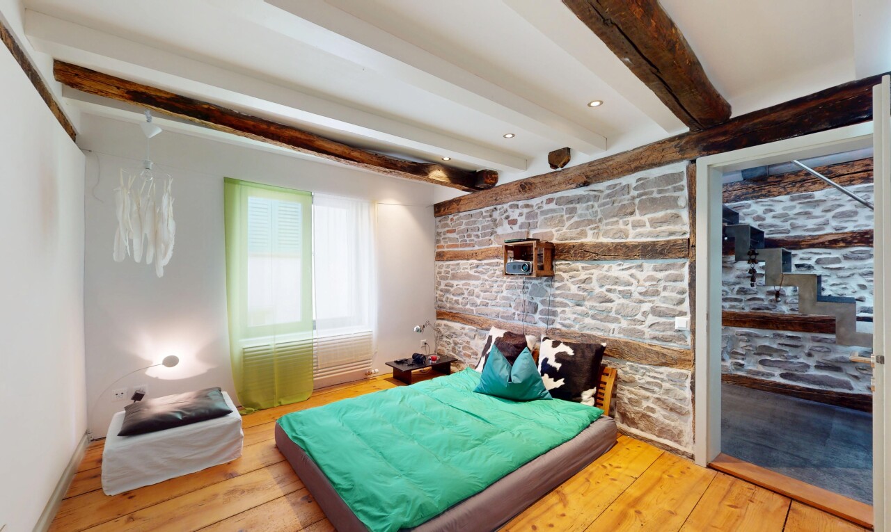 zimmer / schlafzimmer mit gipskartonwand, holzfußboden, steinwand, balkendecke, und natürliches licht