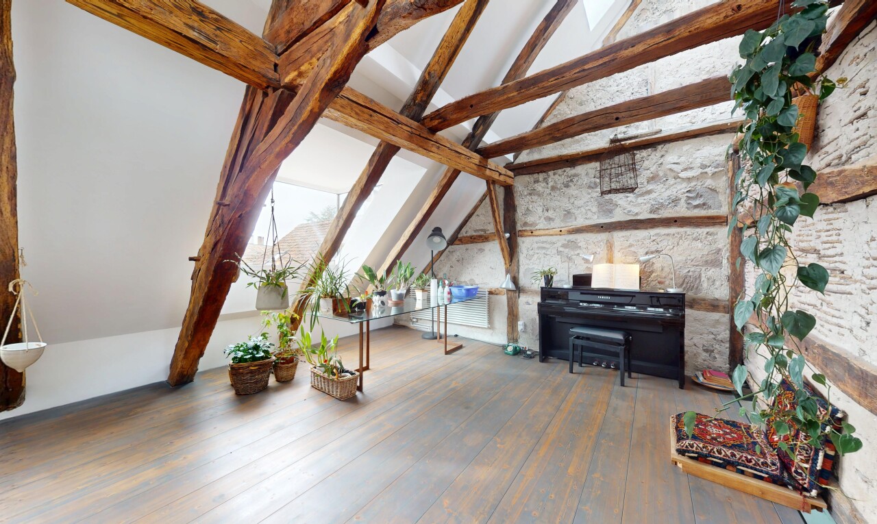innenraum mit steinwand, natürliches licht, dachschräge, balkendecke, und holzfußboden