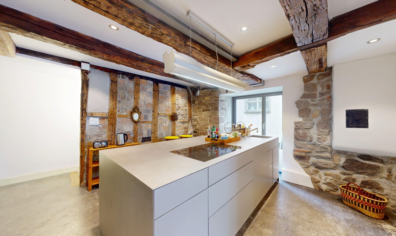 küche mit betonboden, natürliches licht, steinwand, und balkendecke