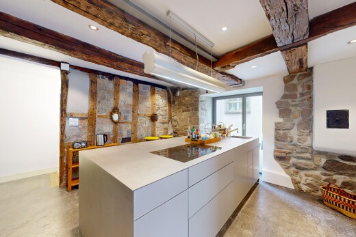 küche mit betonboden, natürliches licht, steinwand, und balkendecke