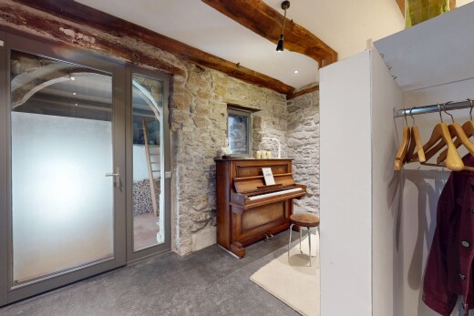 espace intérieur avec sol en béton, mur en pierre, et plafond à poutres