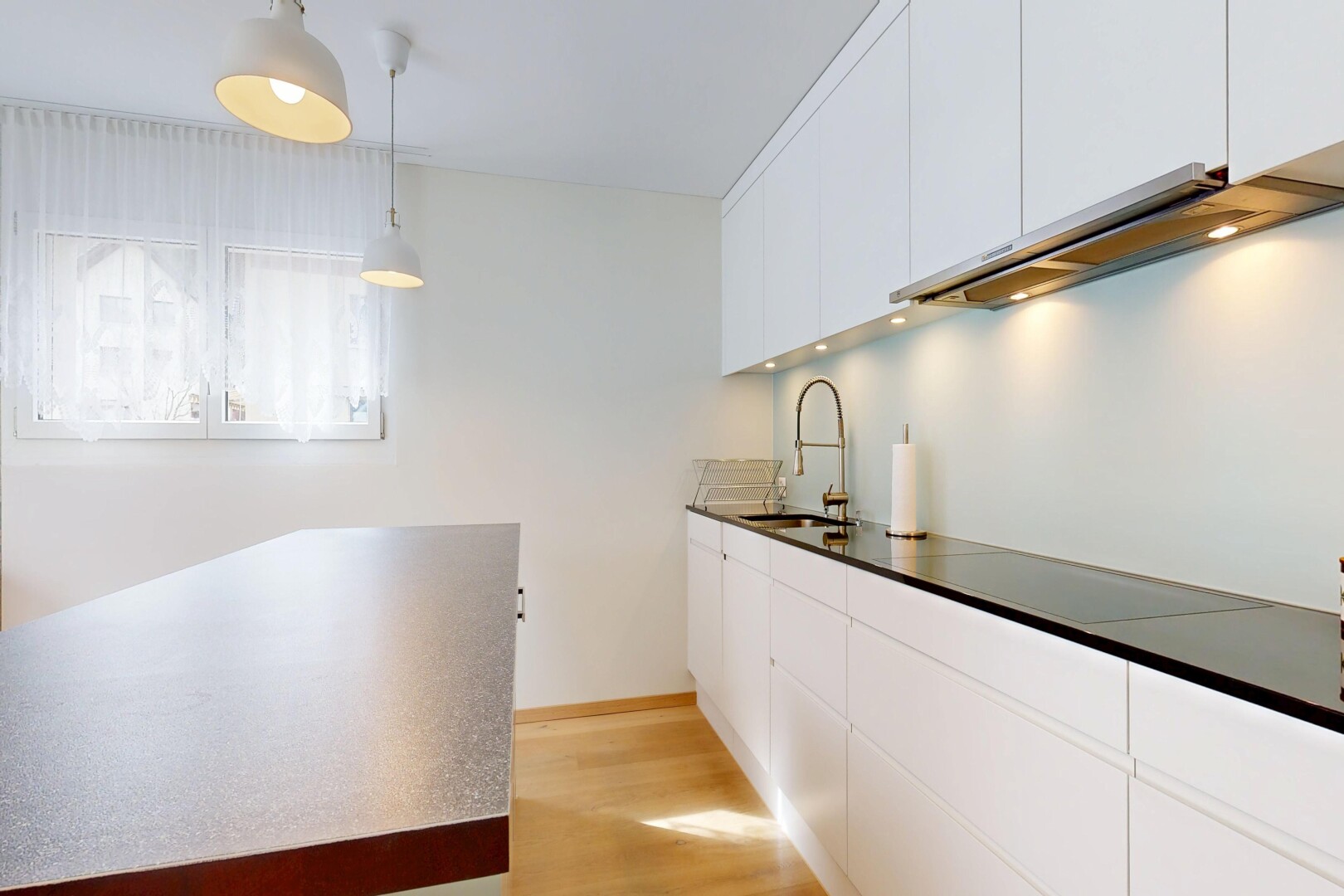 cuisine avec armoires blanches, white cabinets, sol en finition bois, wood finish floor, et éclairage suspendu