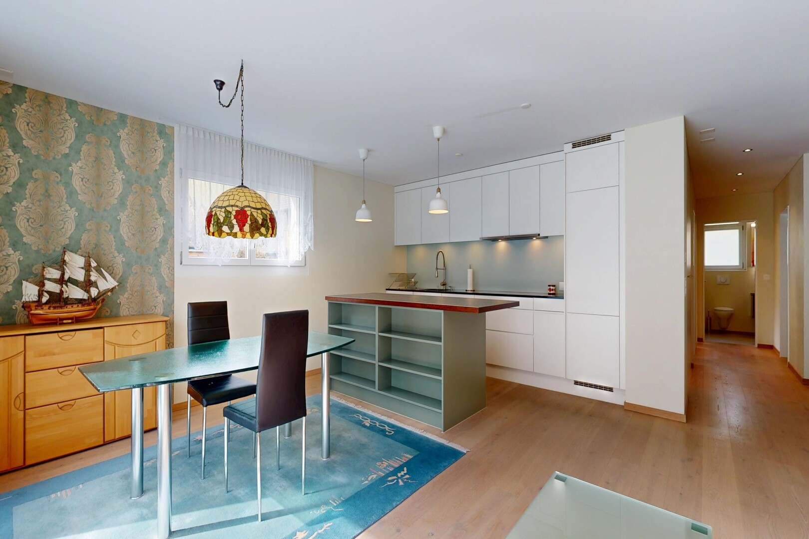 cuisine avec dark countertops, inside property, sol en finition bois, wood finish floor, et armoires blanches