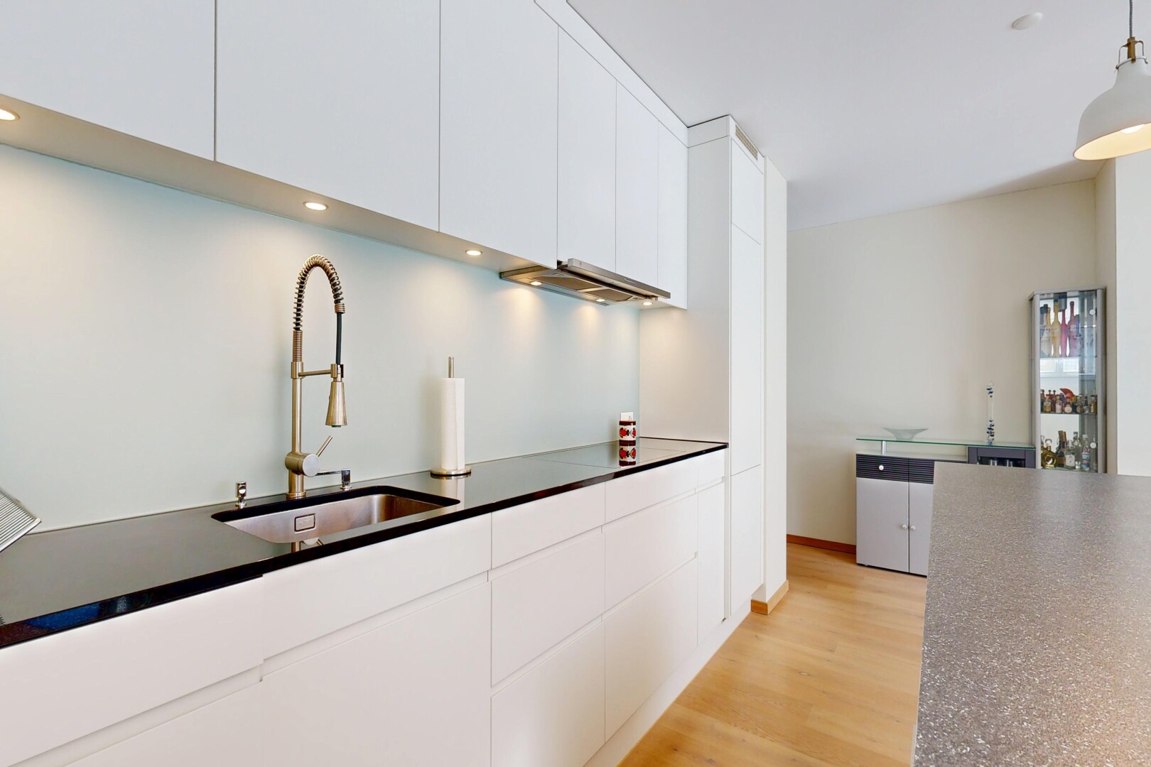 cuisine avec plans de travail, dark countertops, armoires blanches, white cabinets, et sol en finition bois